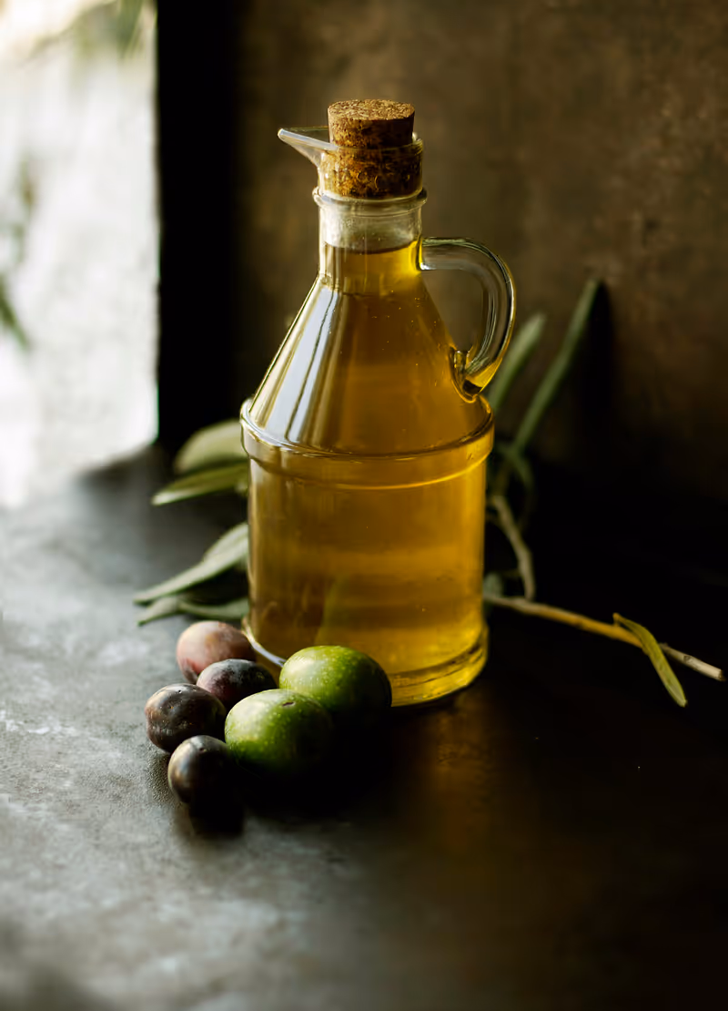 Fresh olive oil being poured from a glass bottle