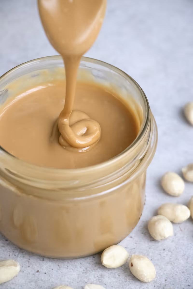Creamy peanut butter being spread with a knife